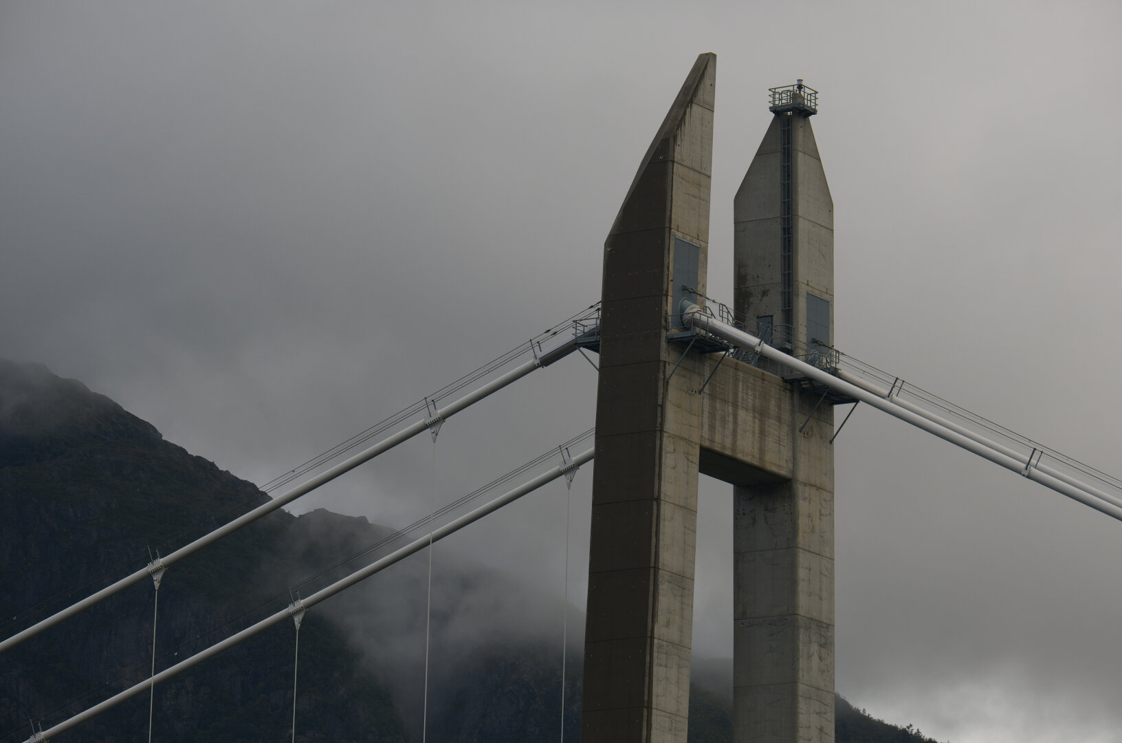 a bridge pillar with a mountain and some clouds in the background