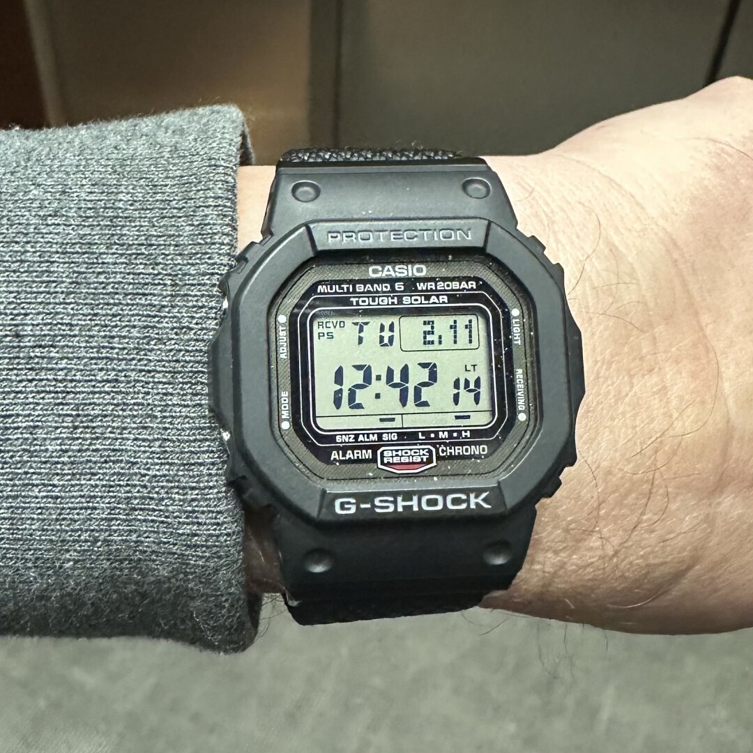 An image with caption: Digital watch with day, date, hours/minutes/seconds, power reserve indicator, octagonal bezel and two function buttons on each side of the case.