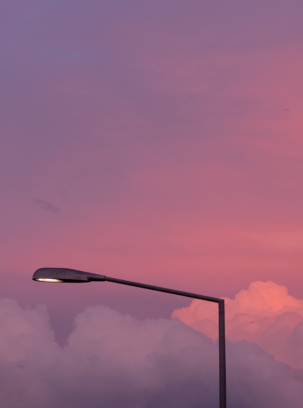 A streetlight in front of pastel colored clouds at sunset