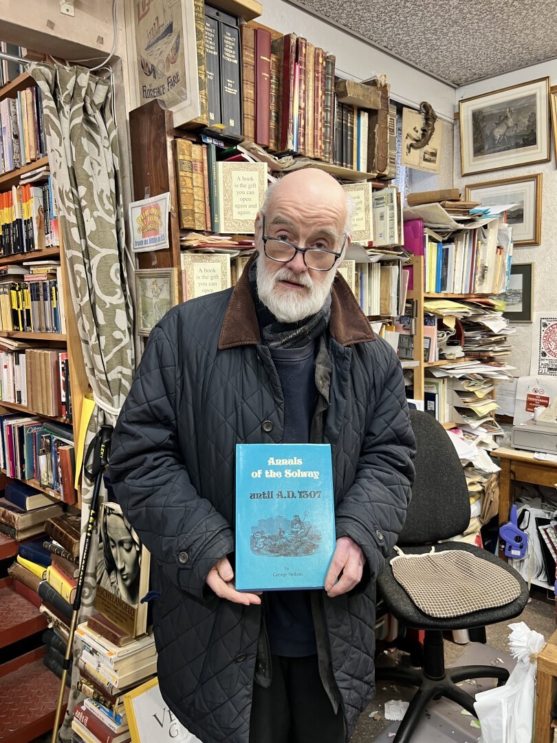 Michael Moon, a bespectacled, bescarfed and becoated finder of new homes for old books, stands near the till in his homonymous shop in Whitehaven (Cumbria, UK) holding a copy of Annals of the Solway (Until A.D. 1307) in its bright blue dust jacket with archival paper, an ill-advised publishing endeavour that has taken many years and as many  misadventures in spelling to tip into profit. Around him, other books.