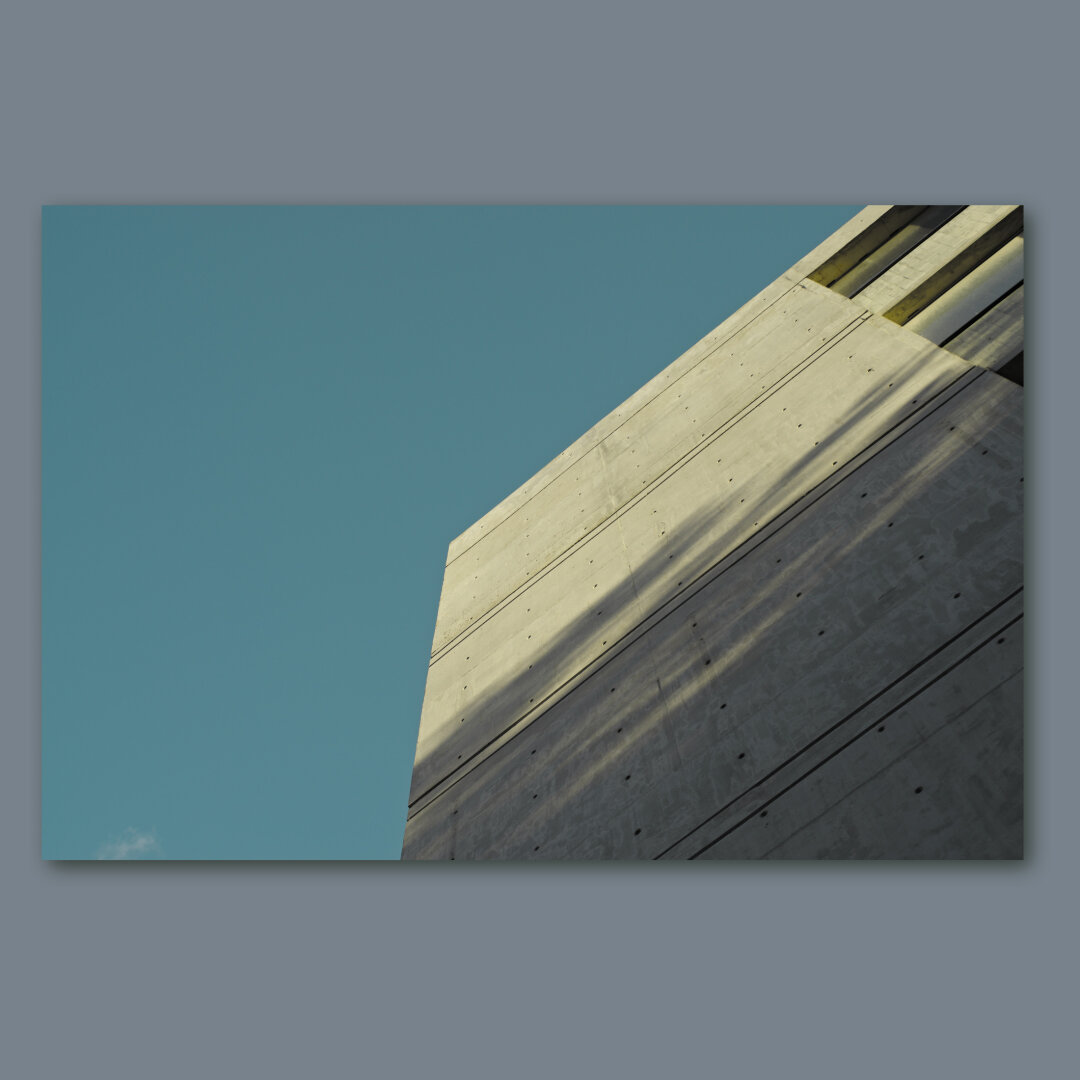 A concrete wall lightened by the sun with the blue sky behind.