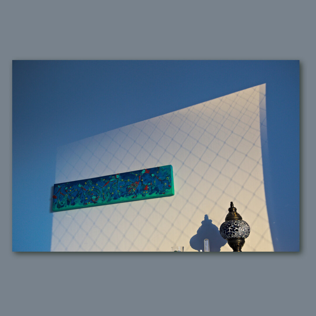 The sunlight over a wall with a painting and a turkish lamp.