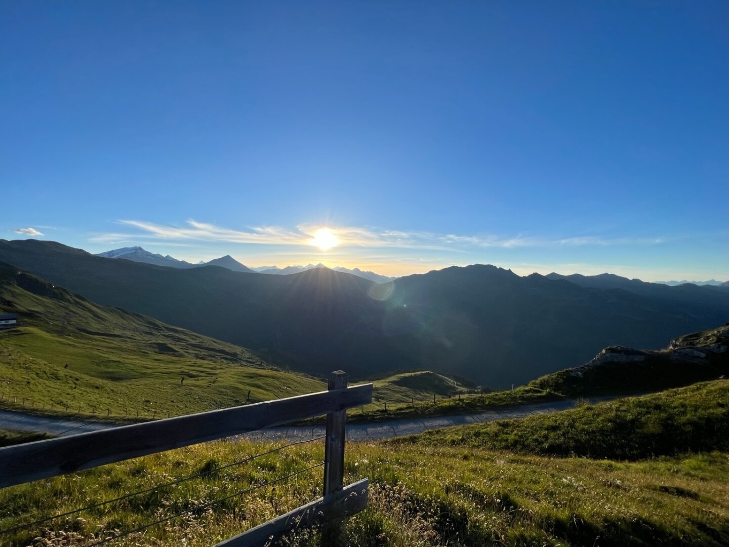 Zu sehen ist ein Sonnenuntergang in den österreichischen Bergen. Noch steht die Sonne über den Bergspitzen.