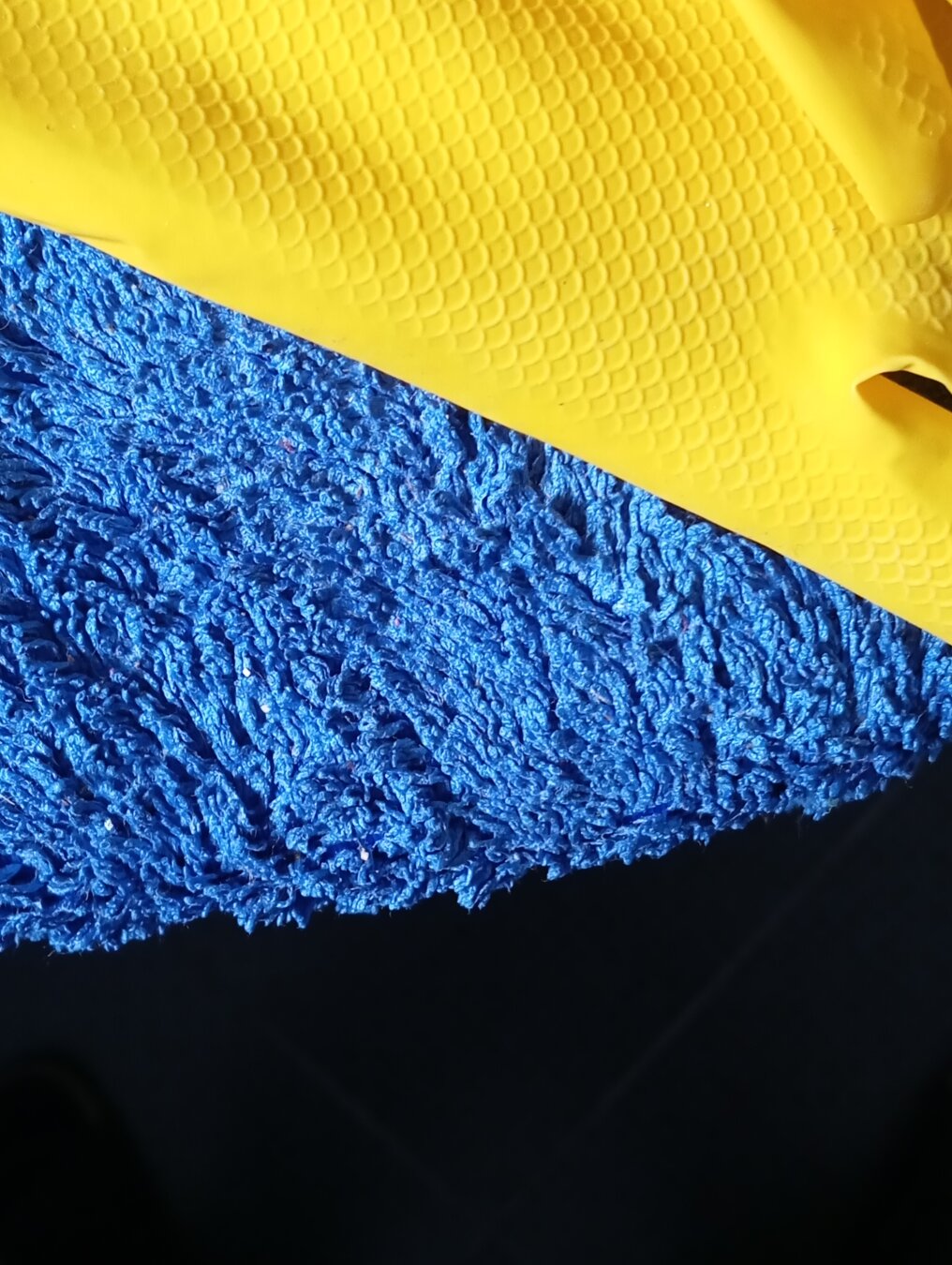 Abstract composition made of blue microfiber rag and yellow household glove.