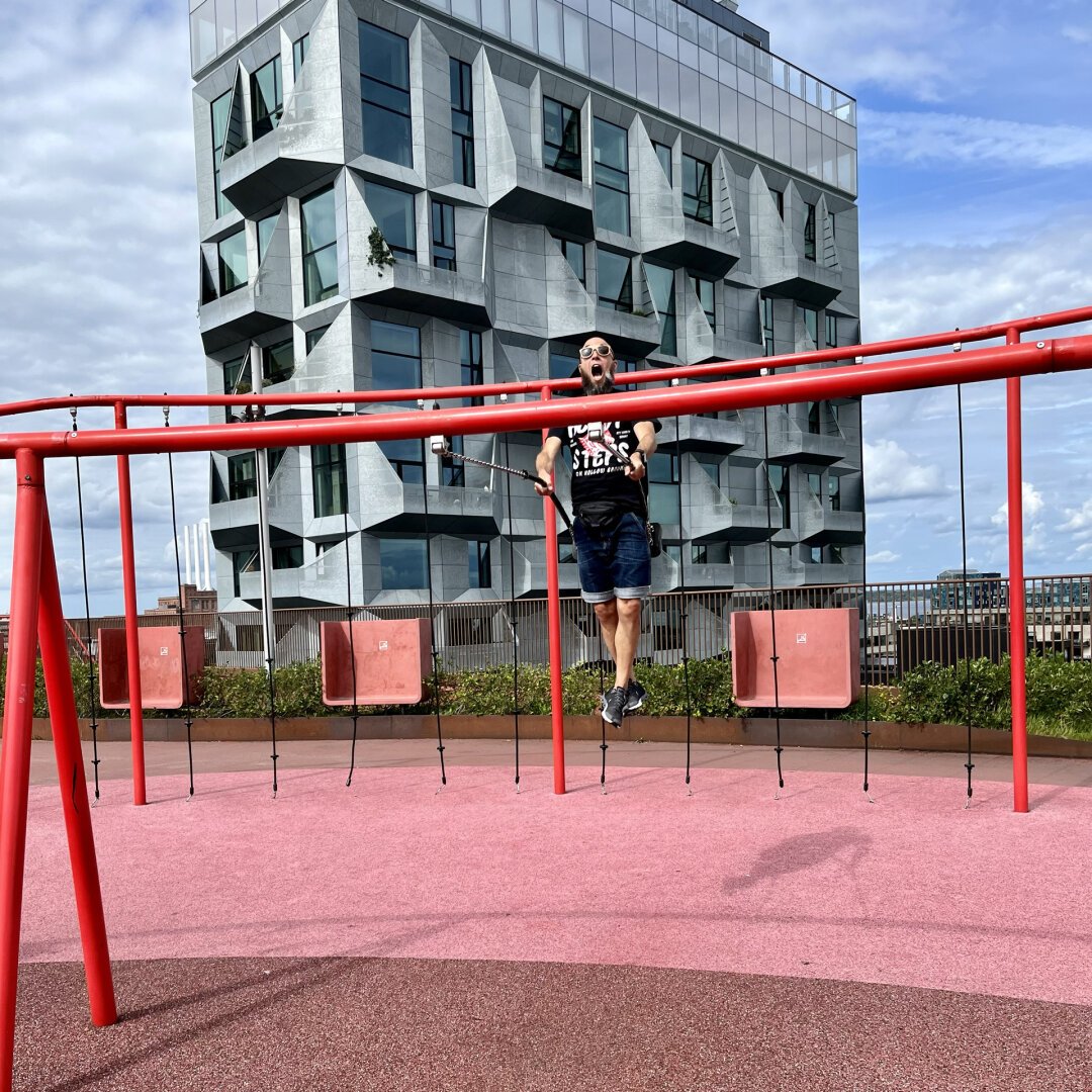 A man swings above the roofs of Nordhavn/Copenhagen with a skyscraper and the harbor in the background