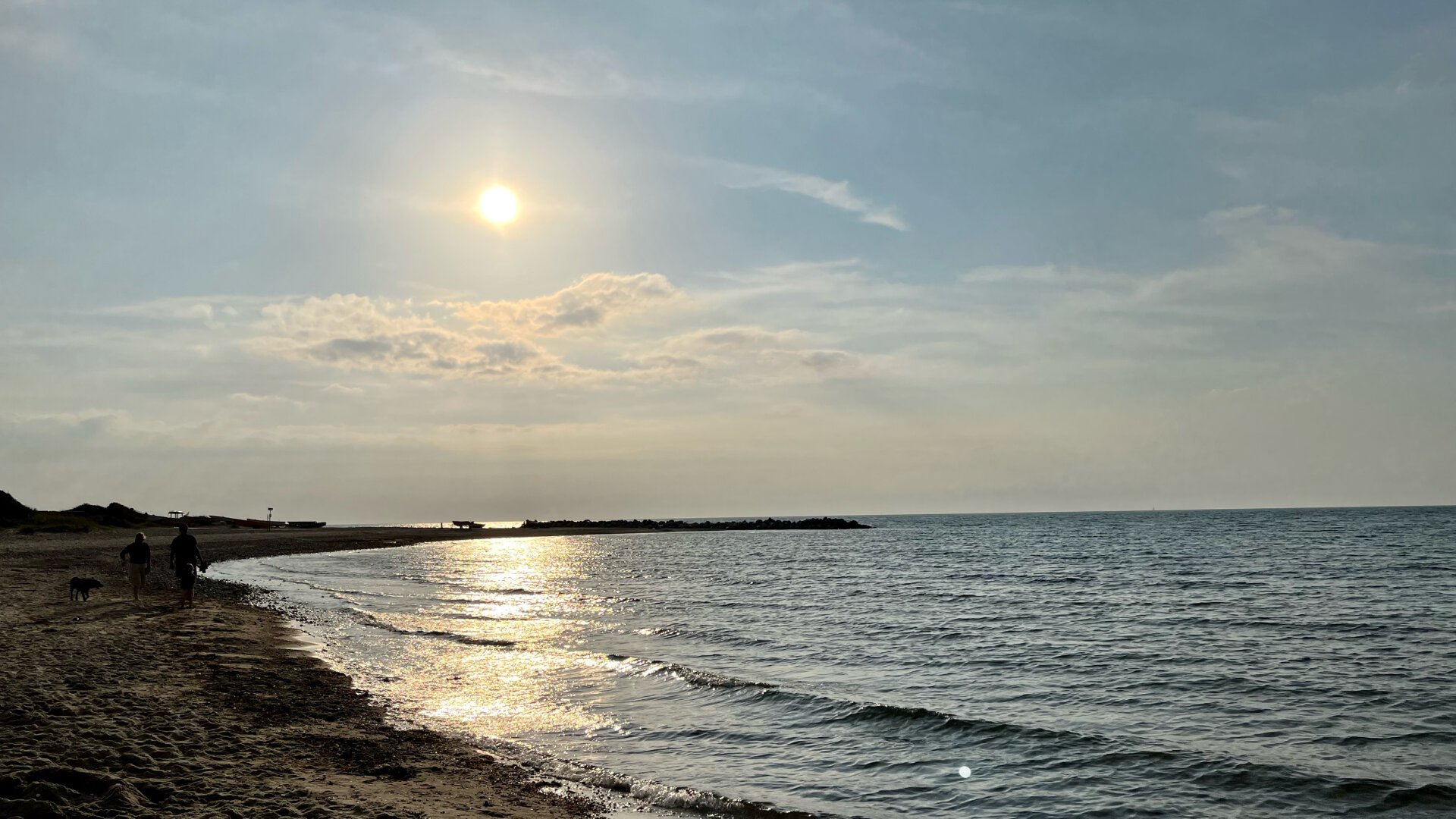 Blick Richtung Abendsonne über dem Meer mit einem kleinen Streifen Sandstrand