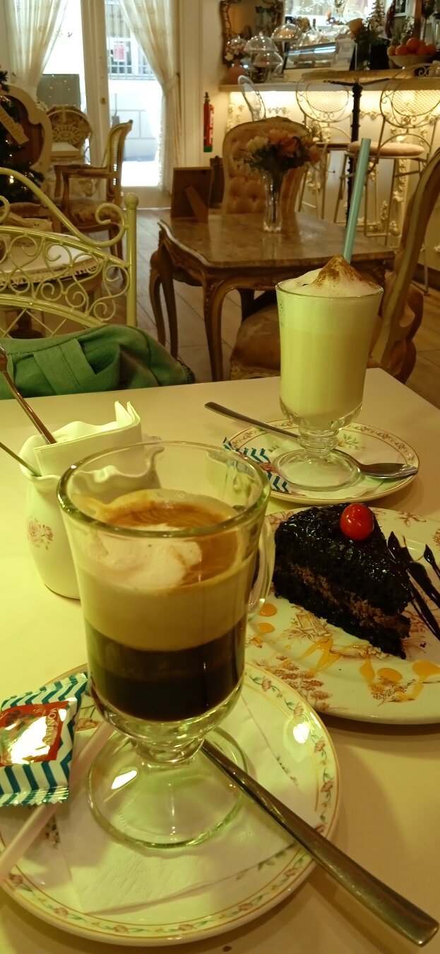 se ven unas copas con café elaborado, leche espumosa y una porción de tarta de chocolate