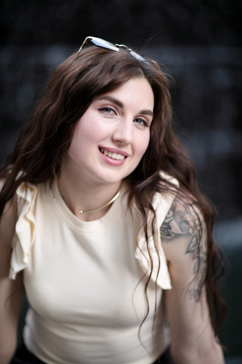Portrait of a young Ukrainian woman, smiling. She is wearing a light outfit, contrasting with the dark background.