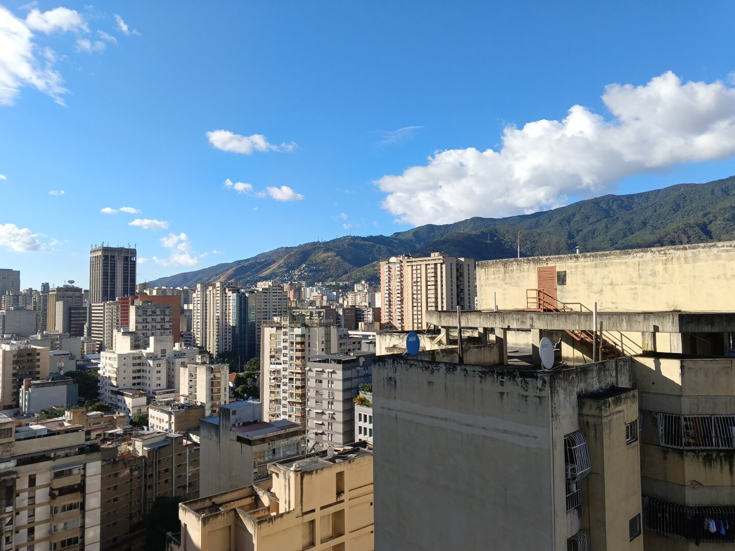 A photo of a city with a mountain backdrop, under a mostly clear blue sky.