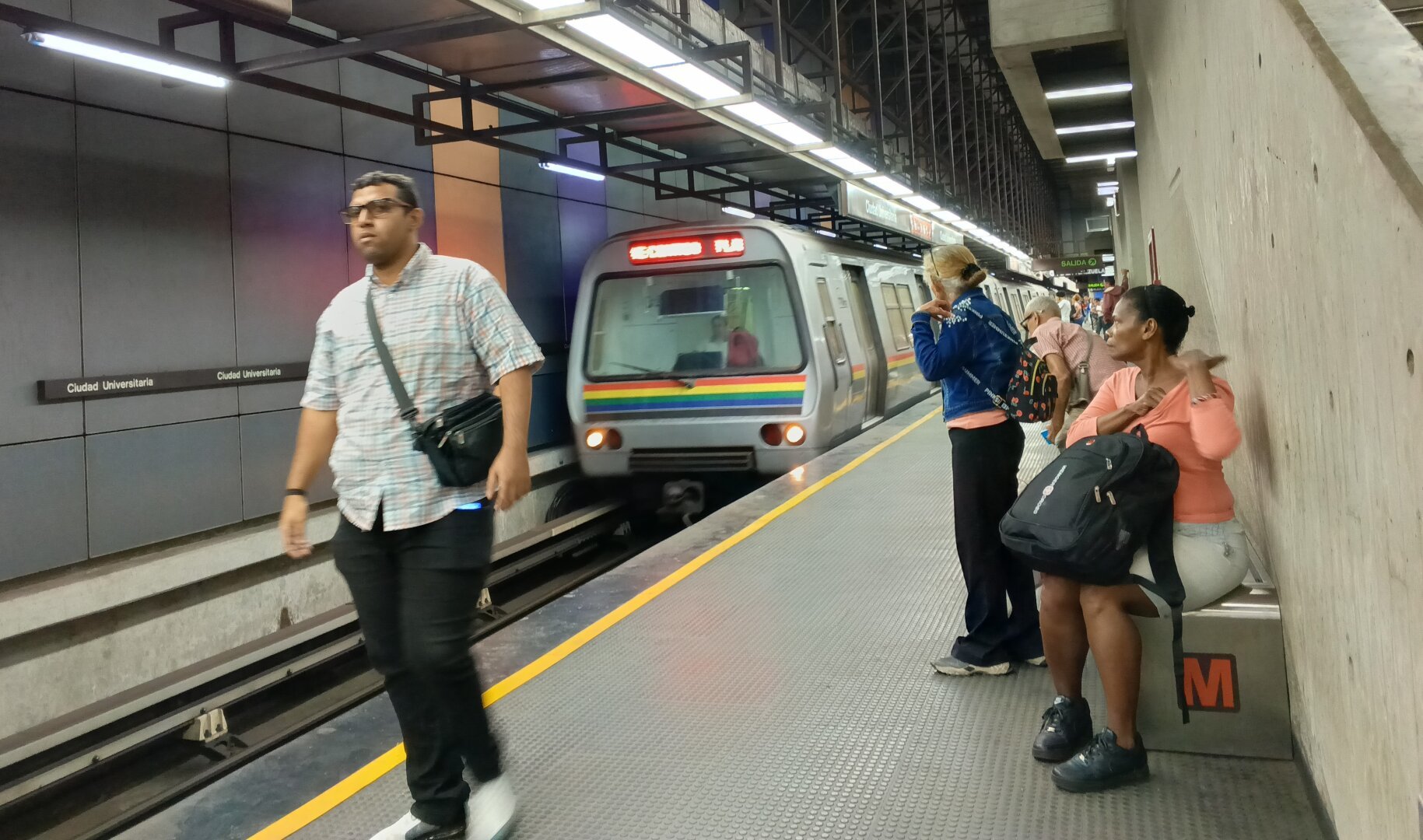 A photo of people going about at a subway station as the train arrives.