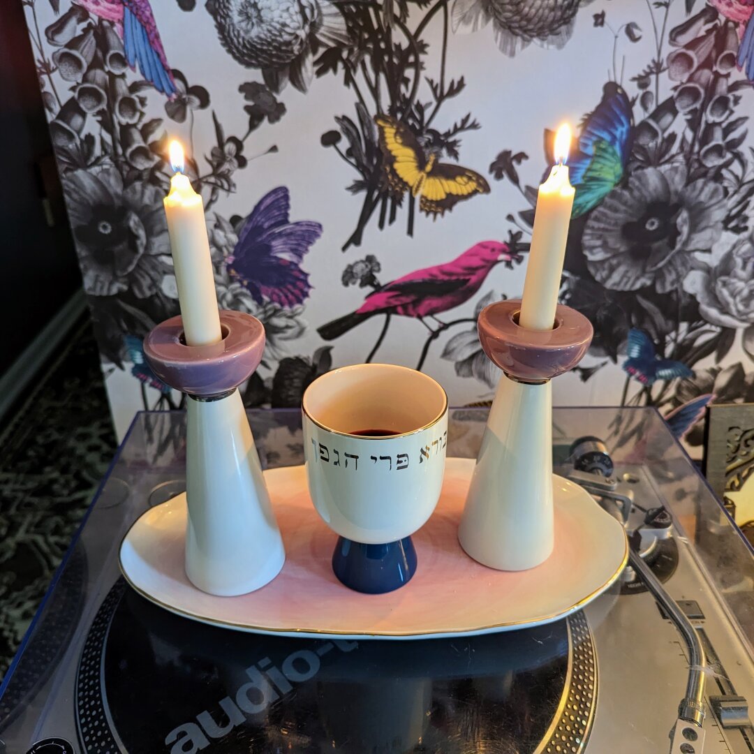 Kiddush cup and Shabbat candlesticks on a ceramic plate.
