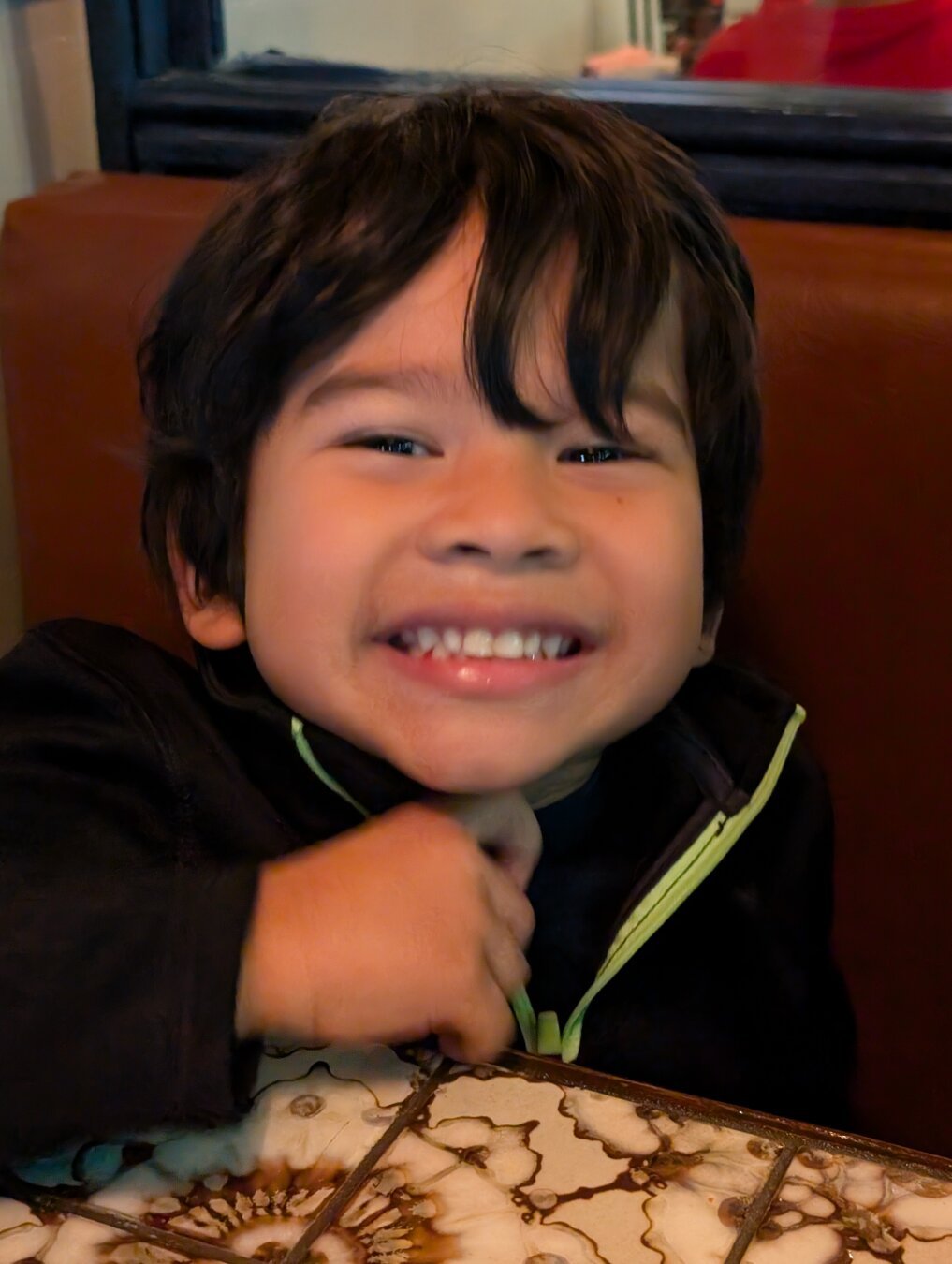 Young boy in a black shirt smiling at the camera.