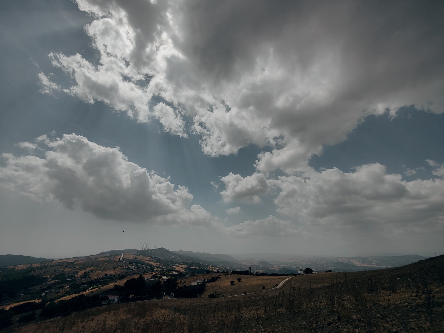 El cielo nublado ocupa las tres cuartas partes superiores de la imagen. En la parte inferior se ve el campo con colores marrones y rojizos y alguna qu otra casa salpicada. El tono de la imagen es frío.