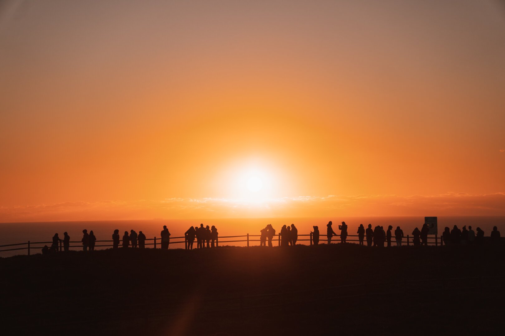 A photo of a sunset, with lots of people silhoutted against it