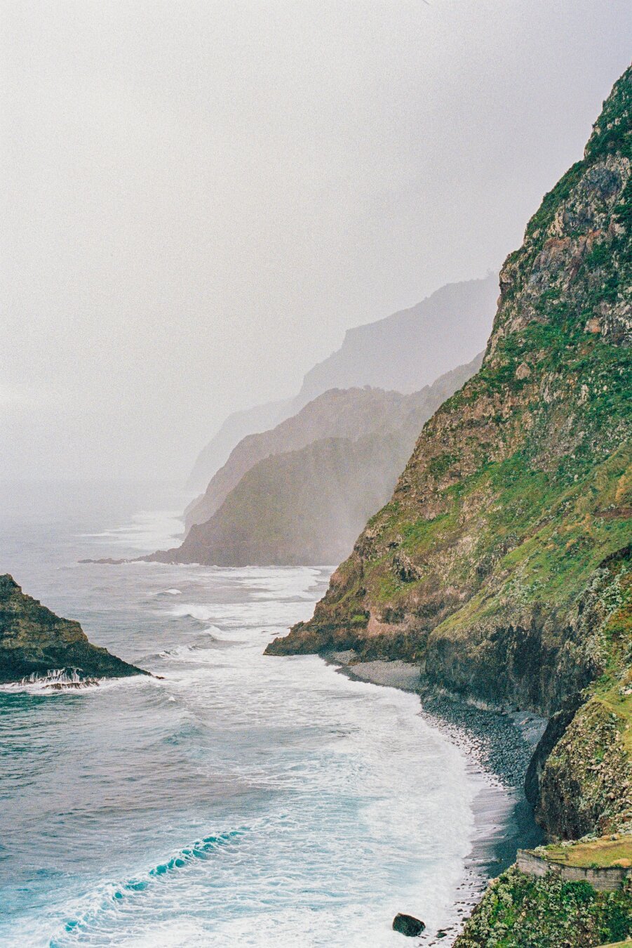 A bay among the rusty green cliffs. Lots of water mist in the air.