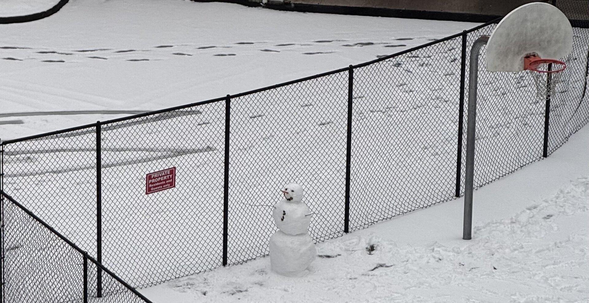 A fresh snowman in a basketball court.