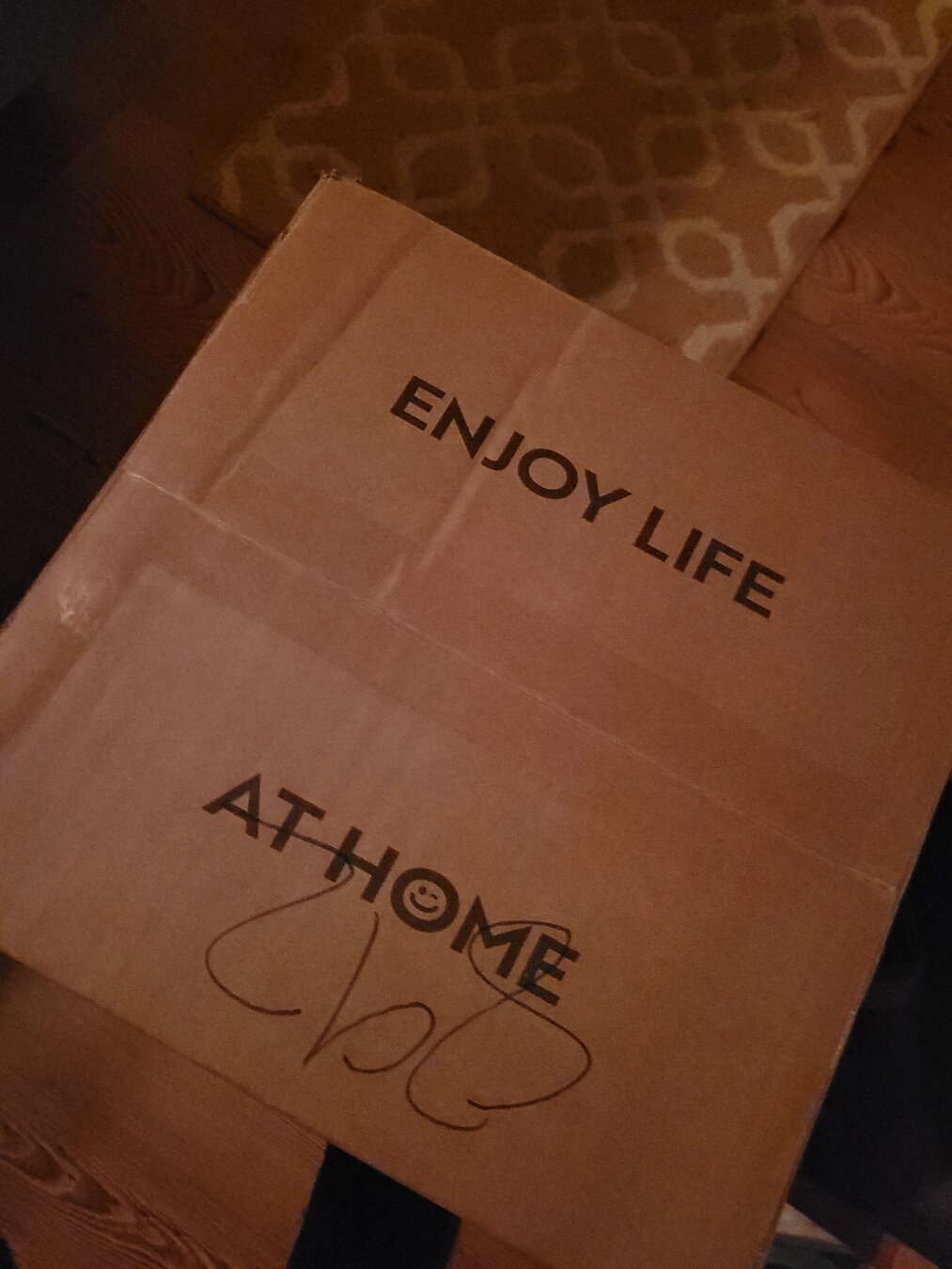 Photo of a cardboard shipping box with text that says "enjoy life at home"