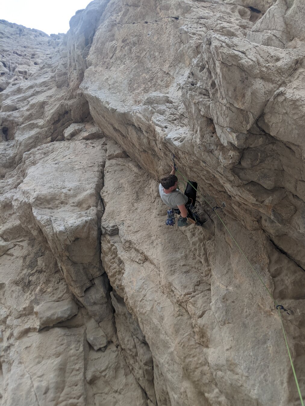 Me climbing under hanging part of the rock with a lot of quickdraws on my harness.