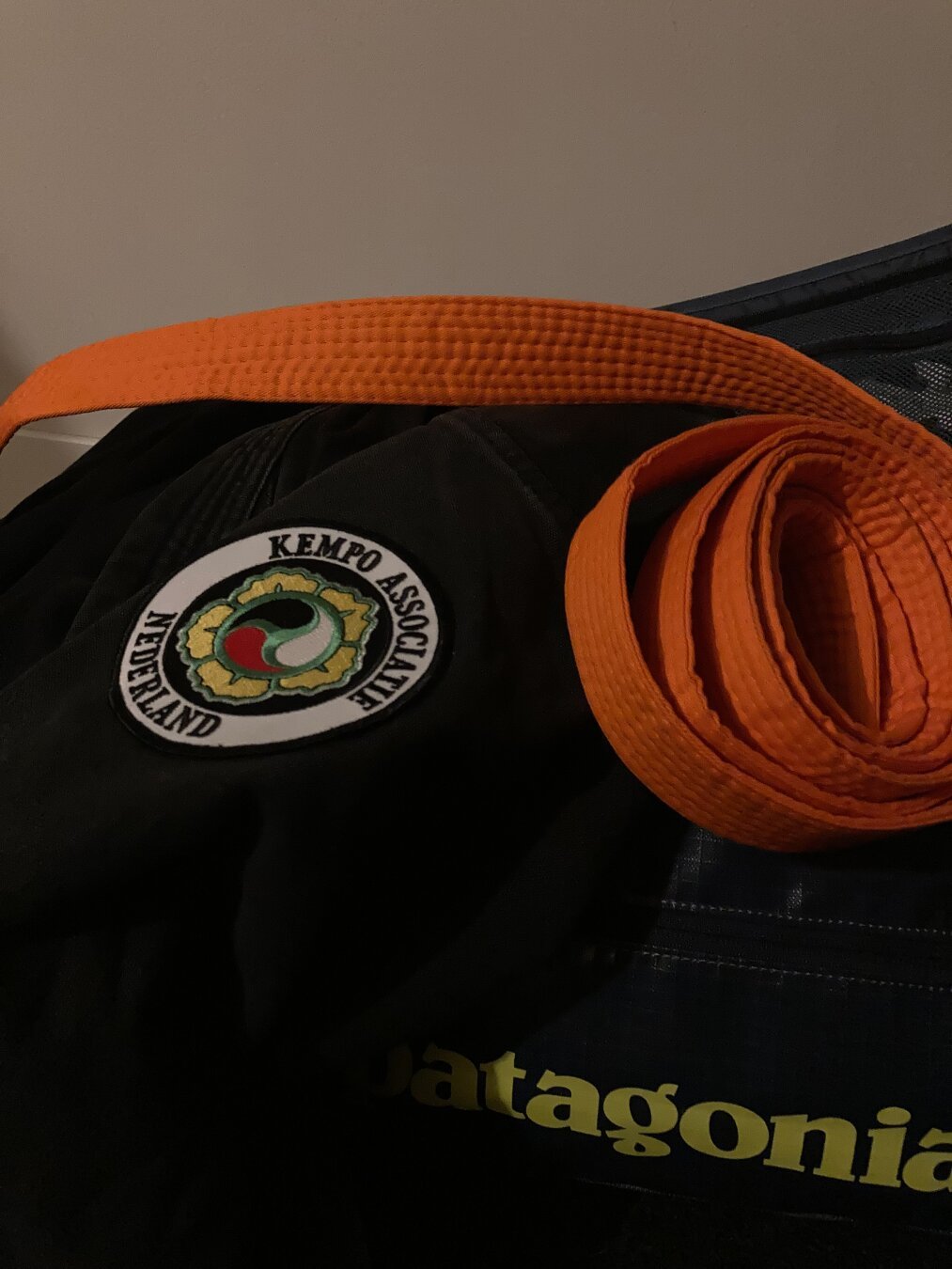 Black kempo jacket with orange belt on top.