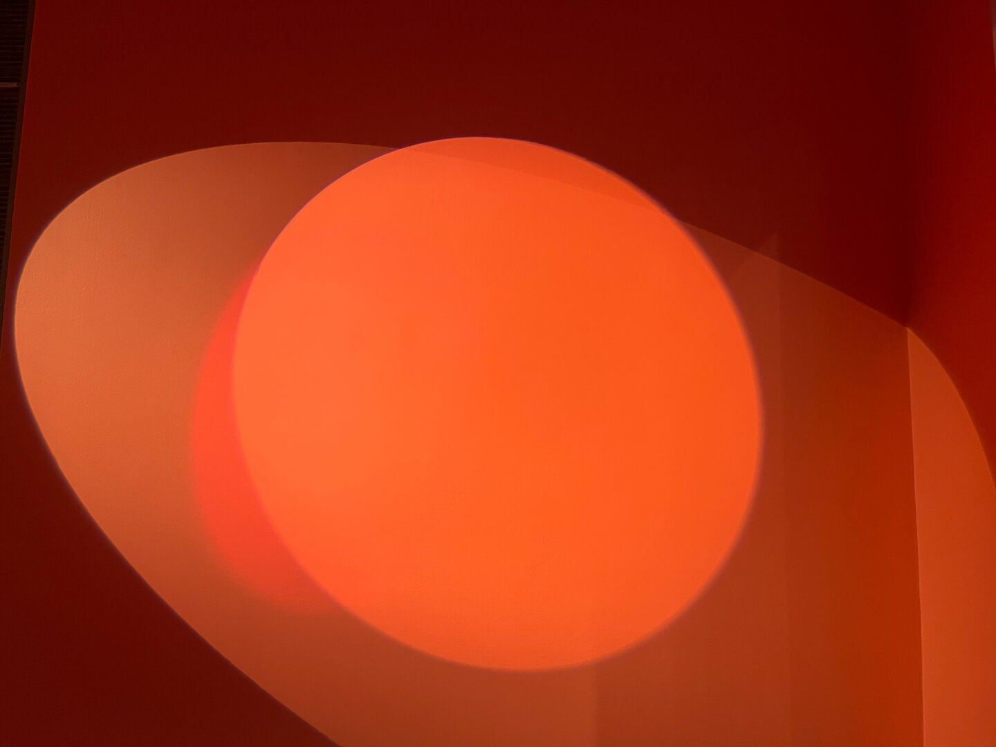 Rounder shapes of shadows of two spotlights on a wall.