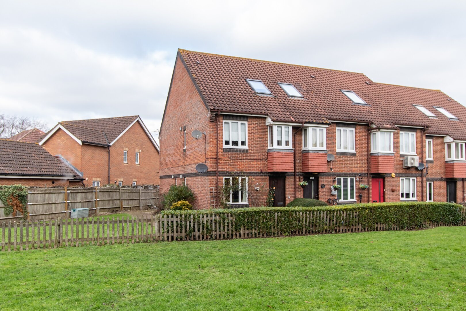 group of small red brick homes with green field in the foreground