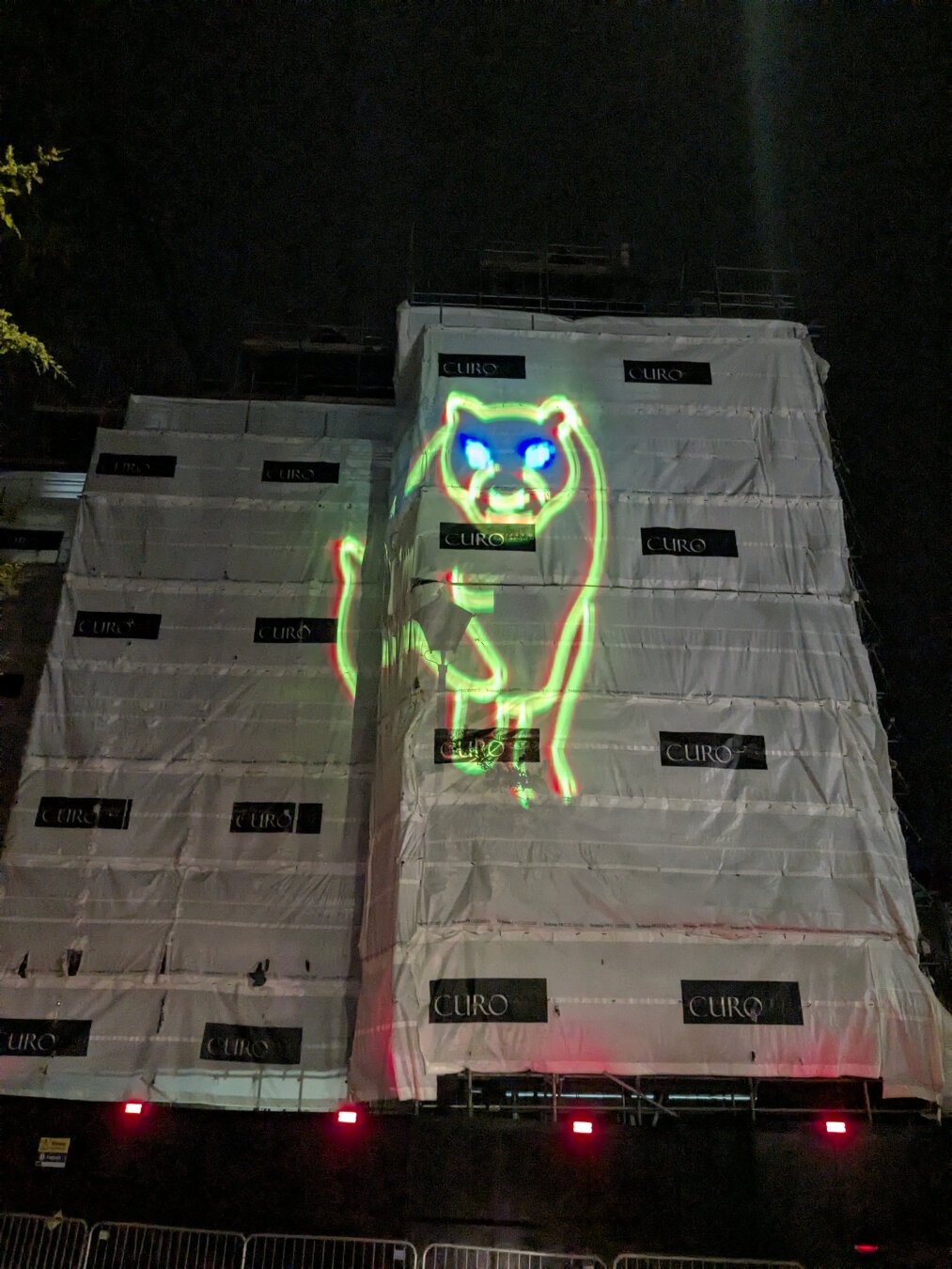 Laser light playing on the hoarding of a new building. The light forms a panther