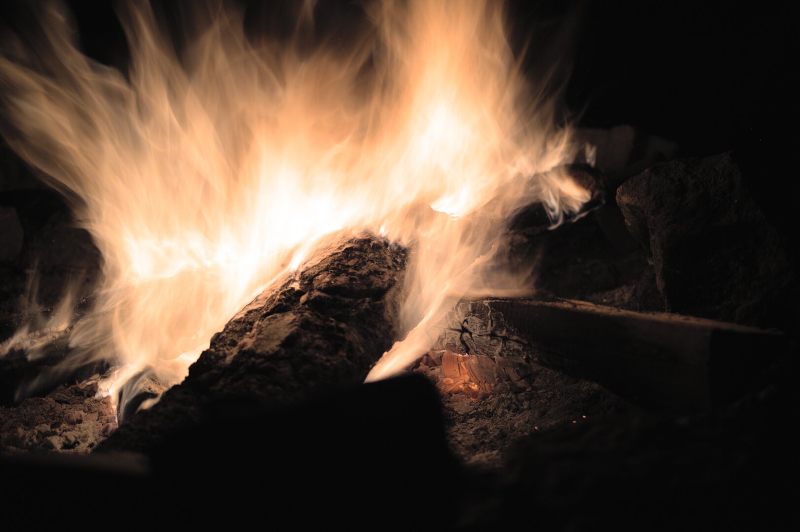 A long-exposure picture of a campfire taken at night. The flames have a foggy, ghostly look to them.