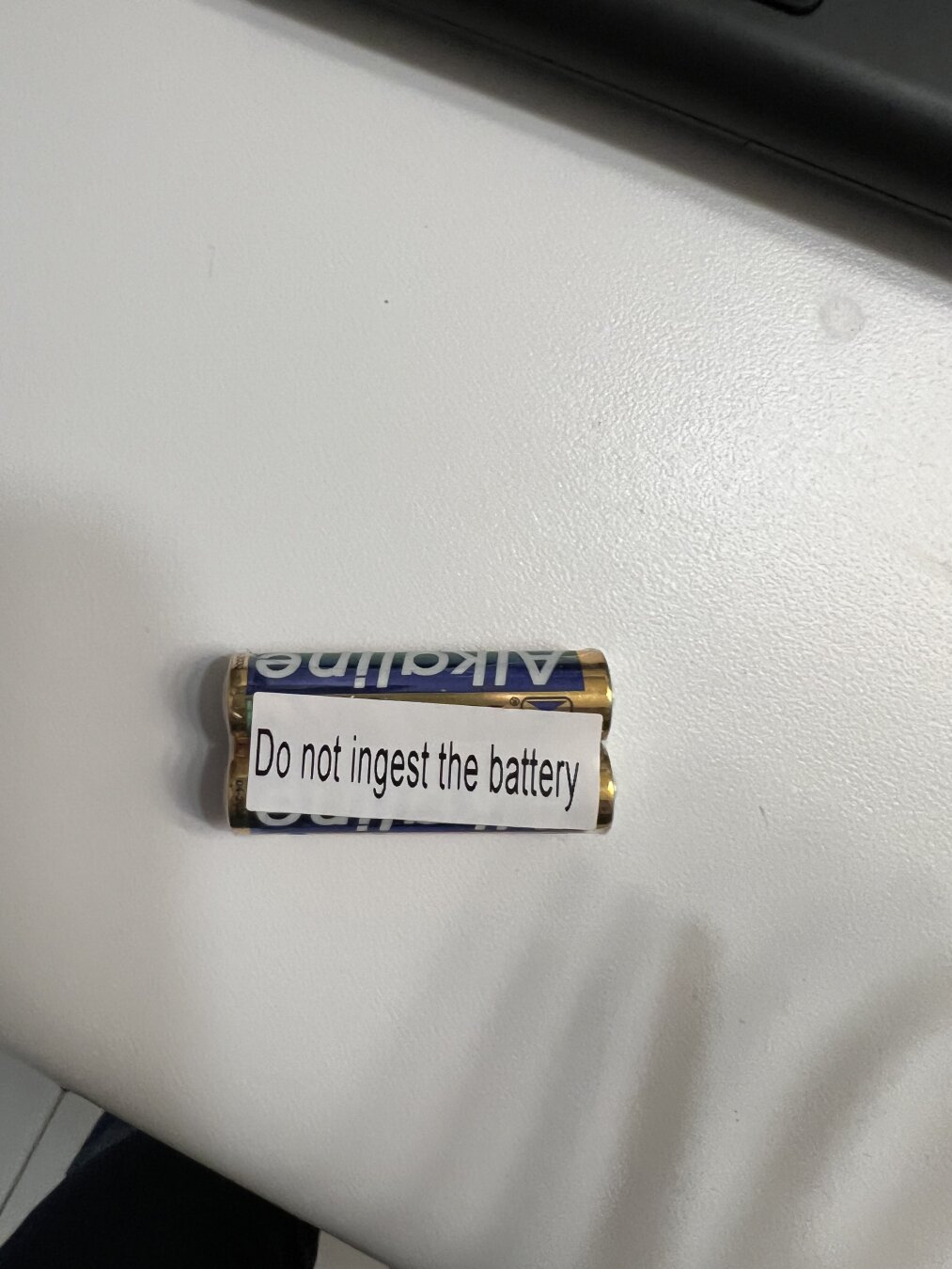 A battery with a warning label that reads "Do not ingest the battery.”