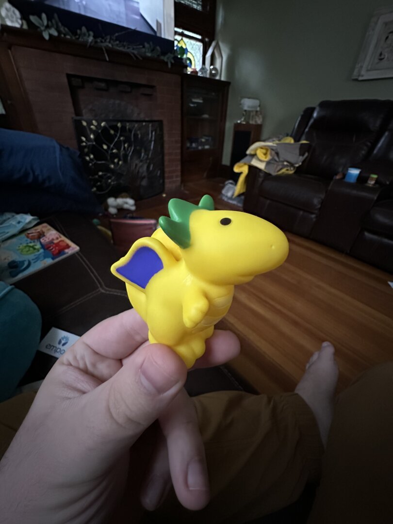 A picture of a yellow plastic dragon with green horns and purple wings.