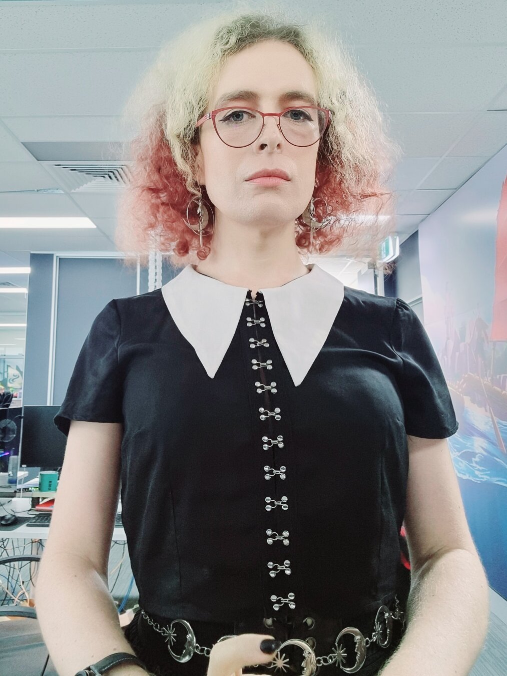 Woman with blonde/ red hair in gothic black top,  white collar and chain accessories