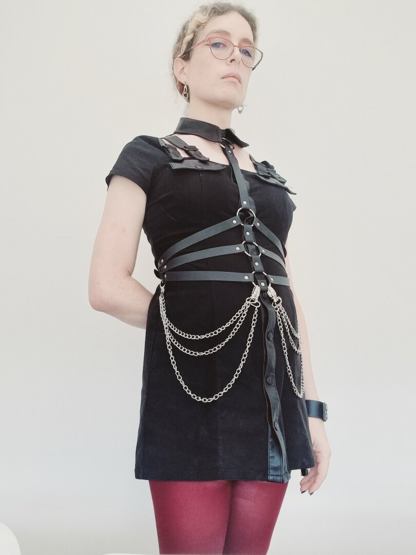 Woman in a killstar dress, chain harness, red tights.