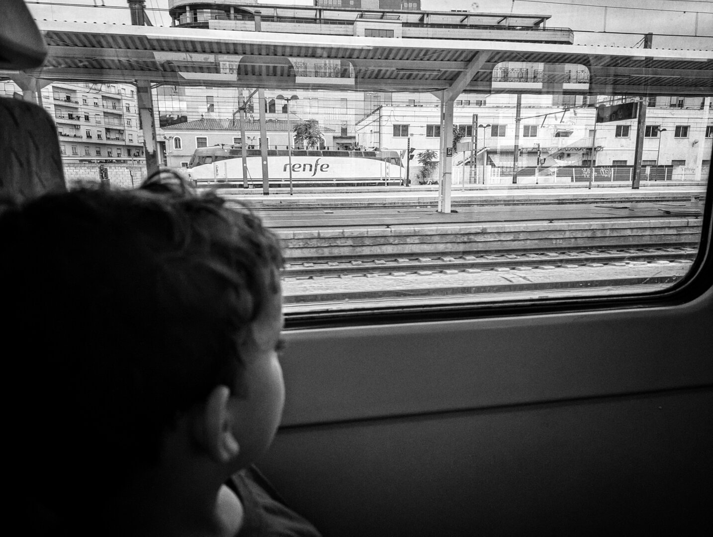 A picture of a kid on a train car looking at the window