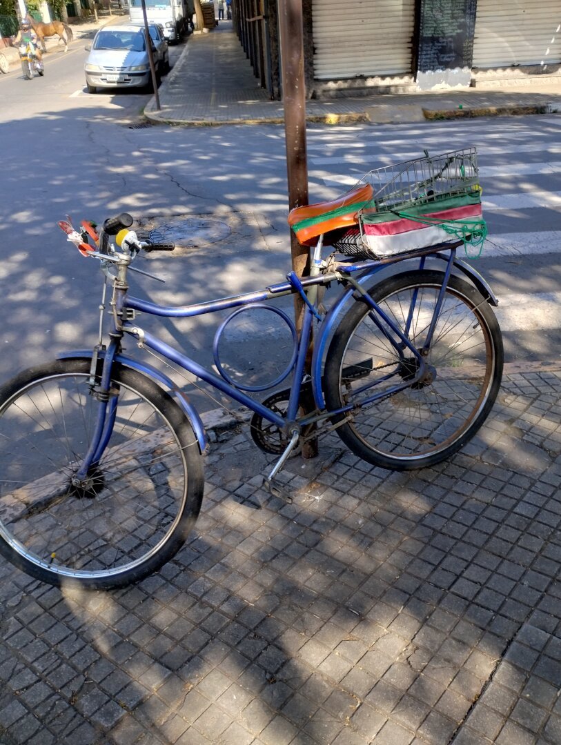 foto colorida, bicicleta modelo barra forte, cor azul presa em um poste