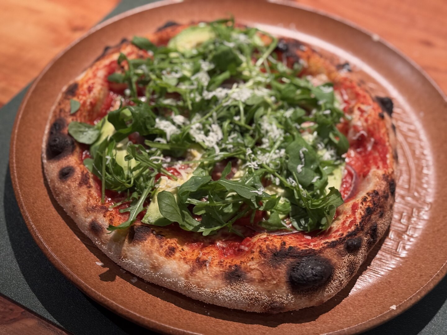 A self made pizza with rucola and parmesan on top