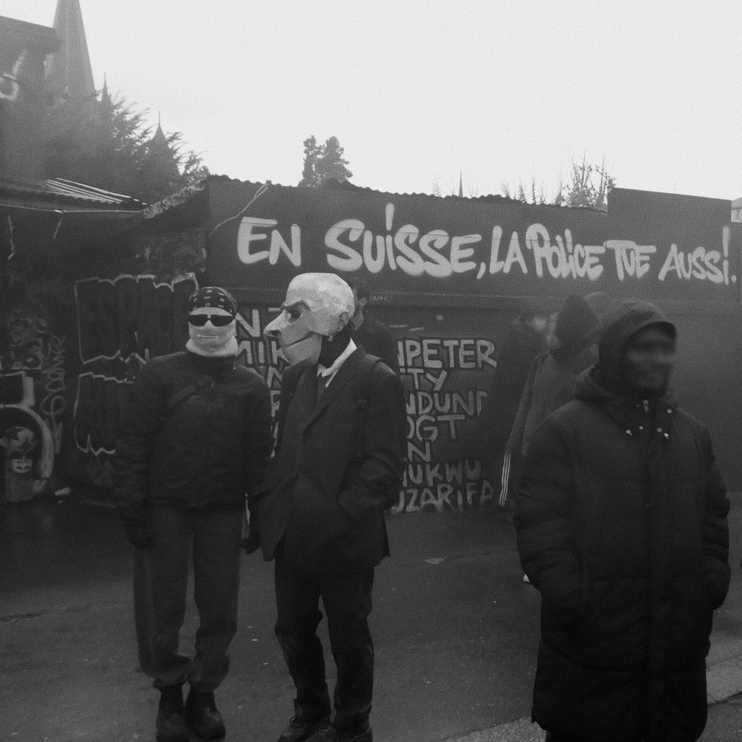 an image from my Pixelfed (because, fuck instagram), shows two people wearing spy masks in front of graffiti wall that reads