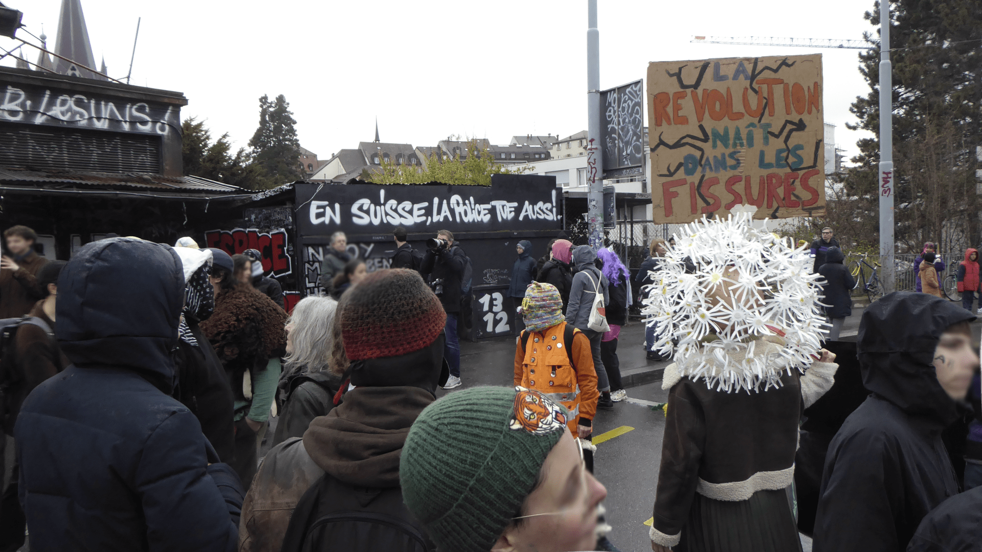 an image from my Pixelfed (because, fuck instagram), shows the antifascist carnaval in Lausanne, in the background on a wall it reads: in Switzerland, the police also kills
