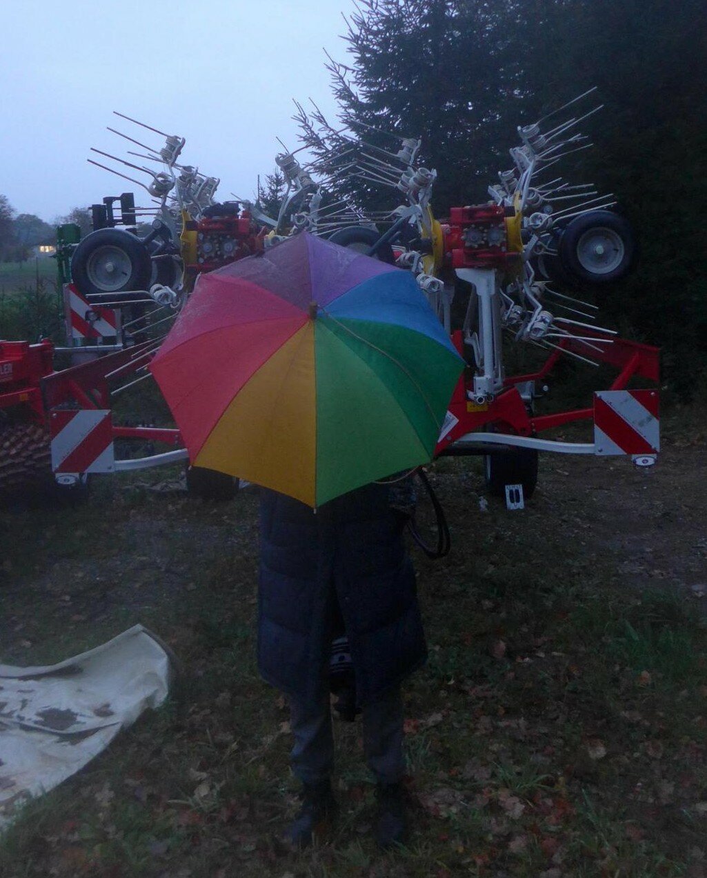 an image or two from my Pixelfed, shows a person with a rainbow unbrella in front of a scary farm machine