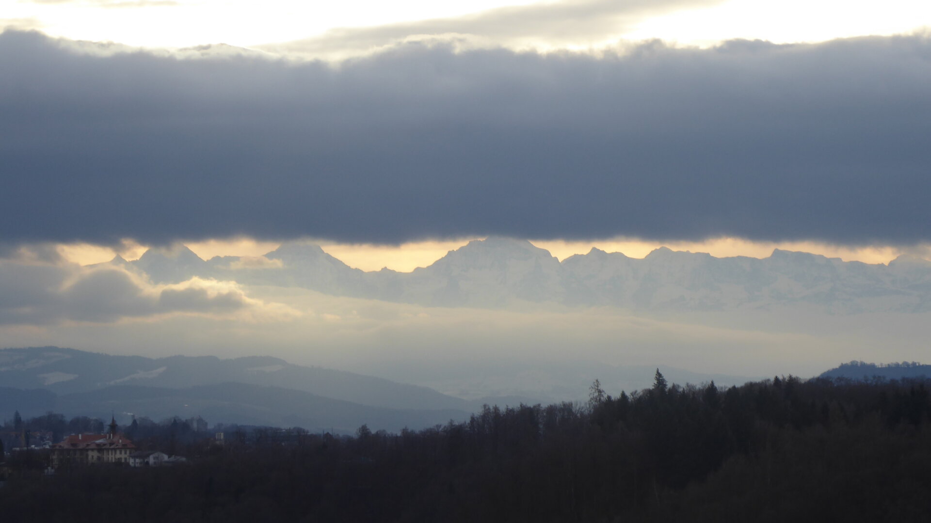 an image from my Pixelfed (because, fuck instagram), shows a mountain range in the morning light half covered by a cloud bank
