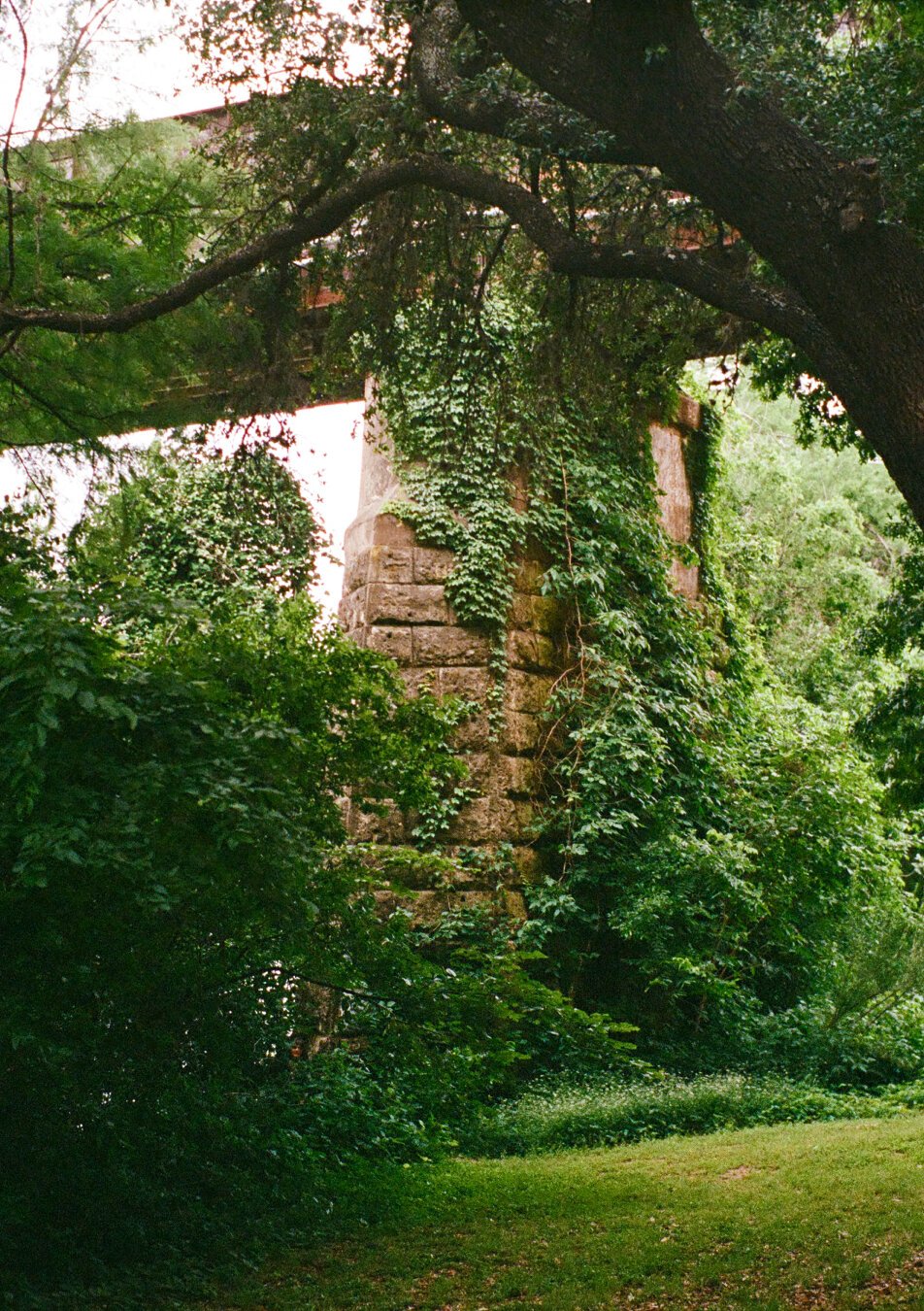 Stone railroad bridge pier surrounded by greenery