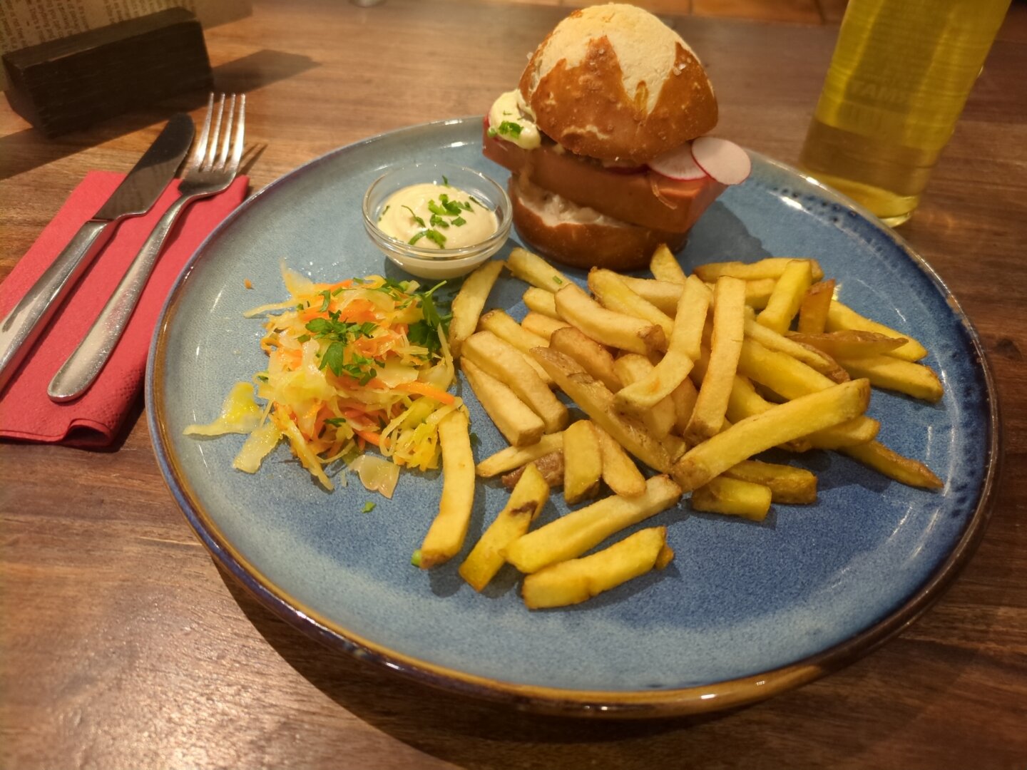 Photograph of the mentioned dish on a blue plate. The plate is located on a dark table. Next to it, there's cutlery on a red paper napkin and a bottle of mate.