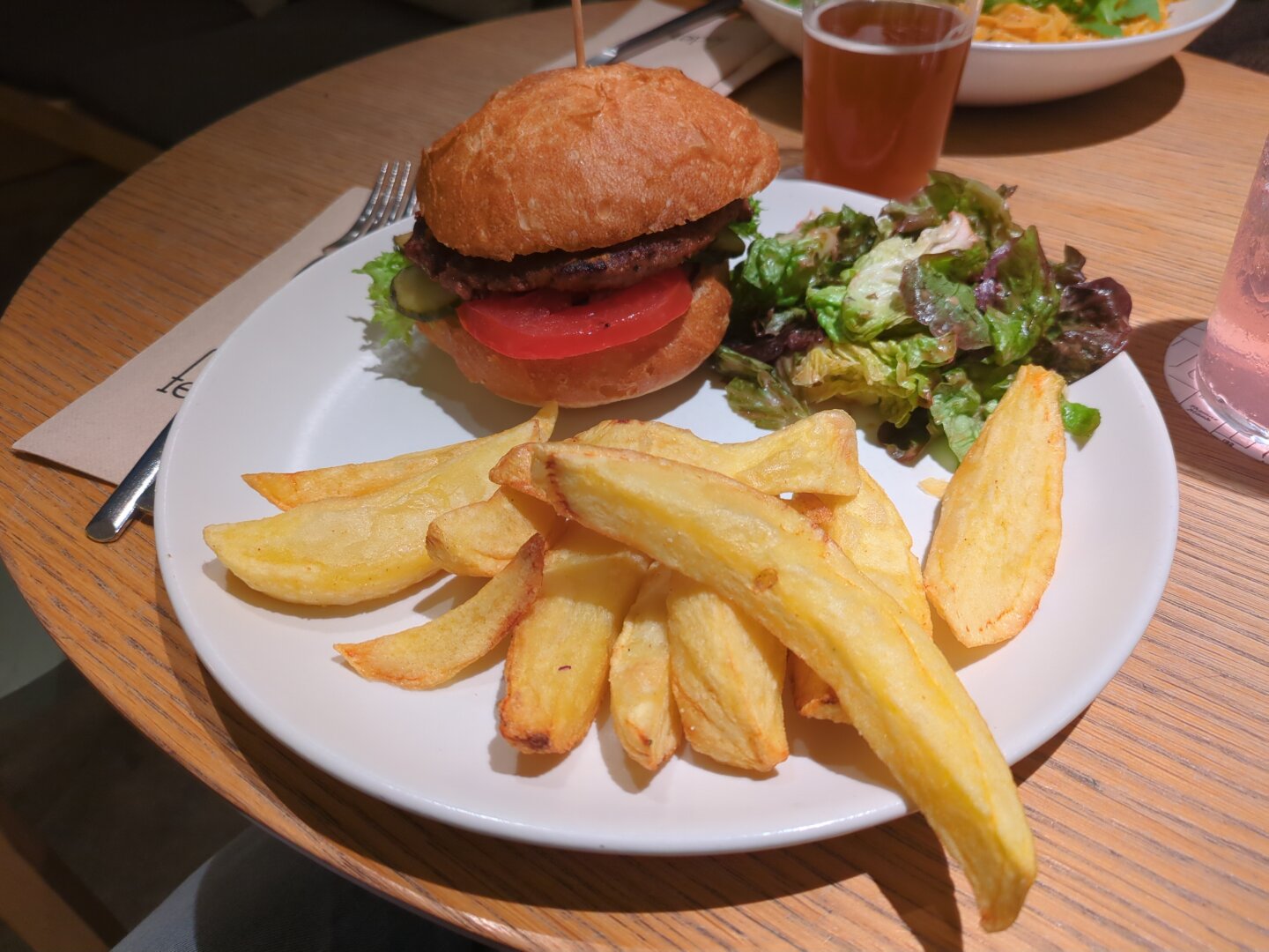 Photograph of a white plate containing the dish mentioned. The plate is located on a wooden table and next to it a glass of beer is visible.
