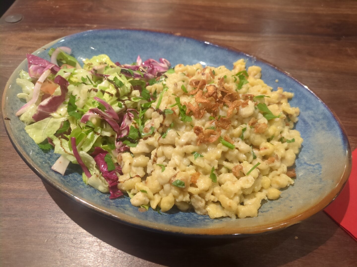 Photograph of a large blue bowl, half filled with salad and the other half with the cheese noodles.