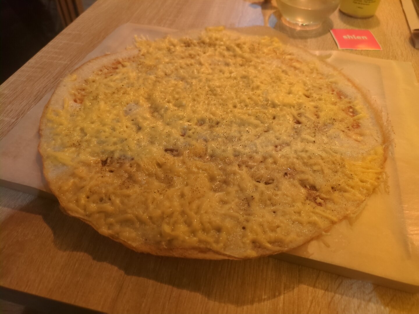 Photograph of the dosa, also arrange on a paper covered wooden board. Its a flatbread made from fermented rice and lentils and contains molten (vegan) cheddar cheese.