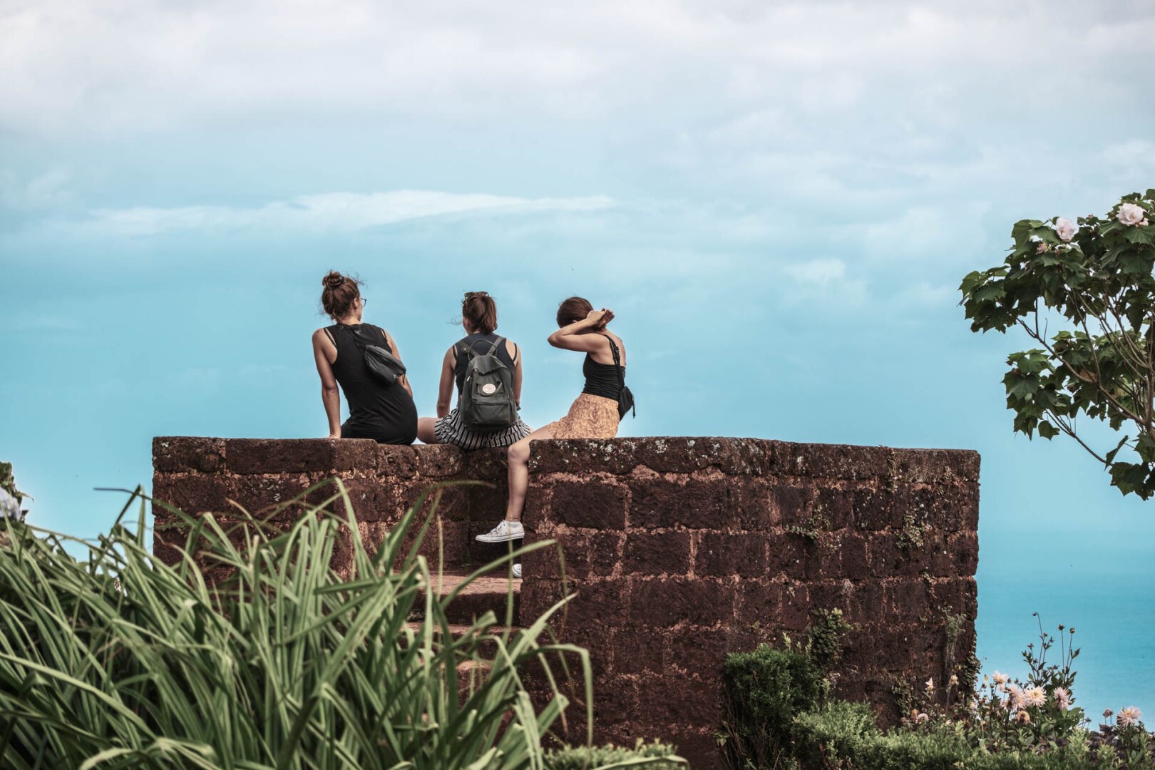 a group of women sitting on a stone wall