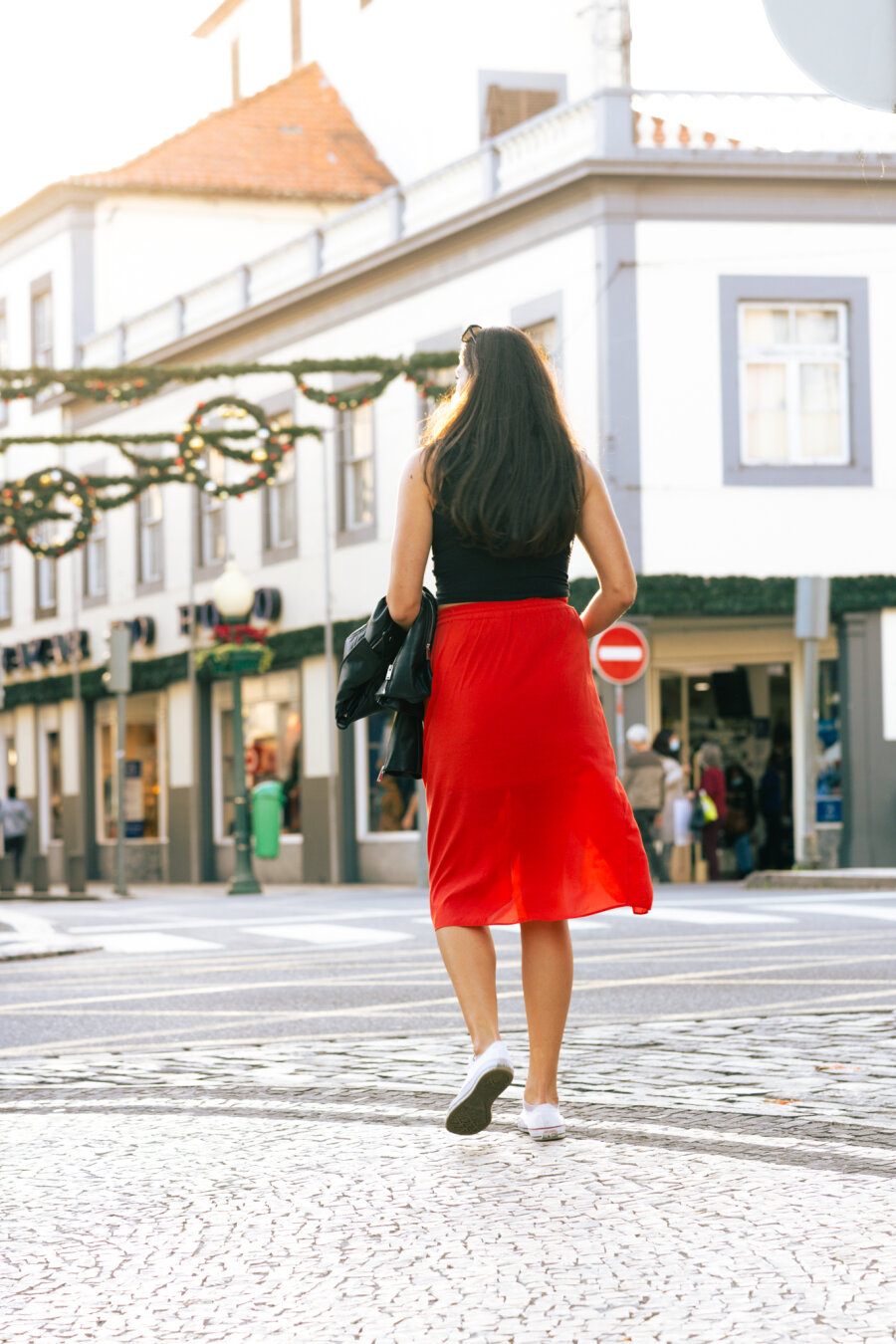 a woman in a red skirt crossing the street