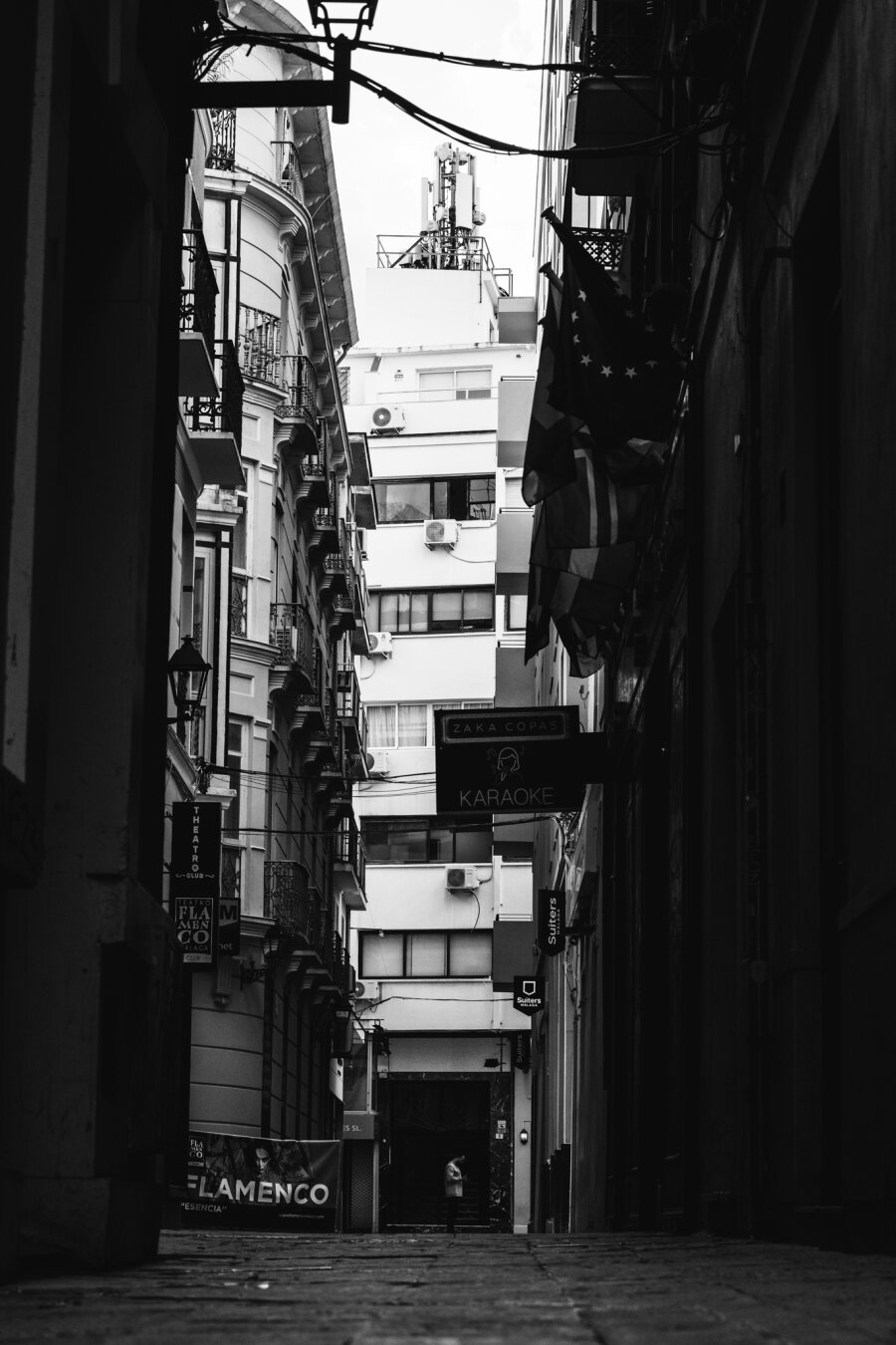 a man taking a smoking break, looking at his phone, between tall buildings