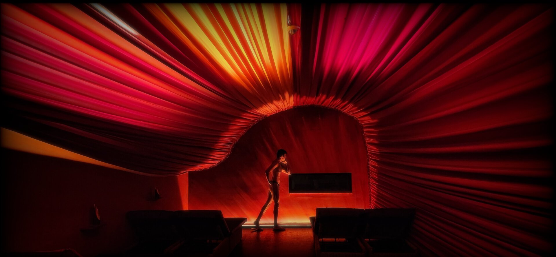 Posing in a red covered and dimly lit room.