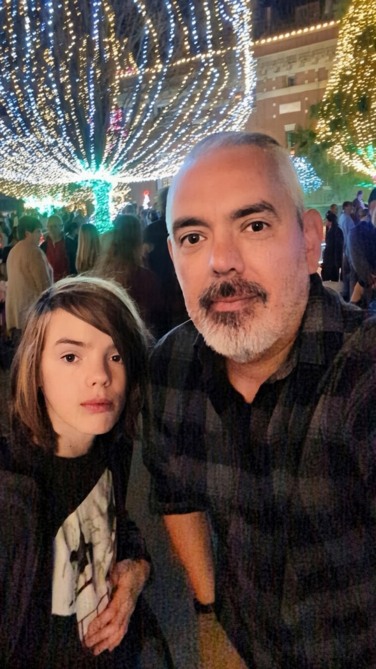 A father and son in front of Christmas lights