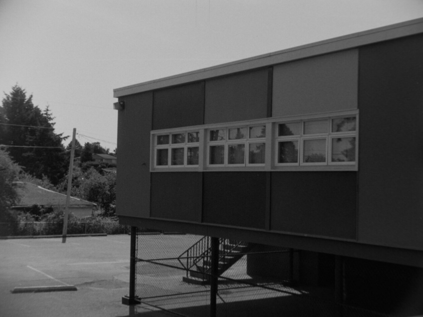 The same building but a corner that extends over a low hill, stilts hold it up above the parking lot.