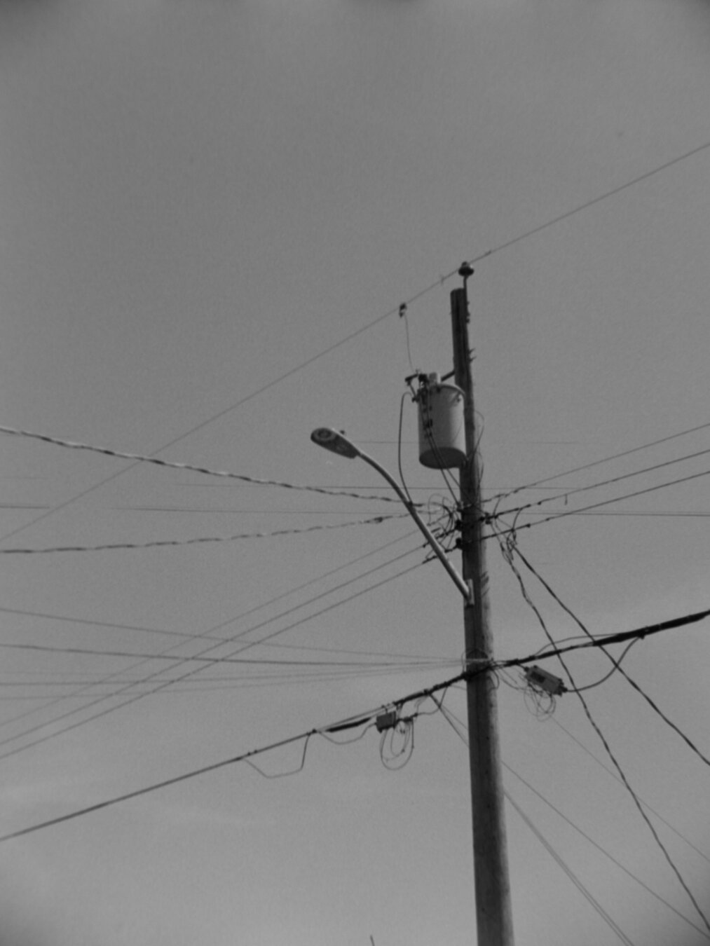 A utility pole, withe lines running left and right. A lamp and transformer adorn the top.
